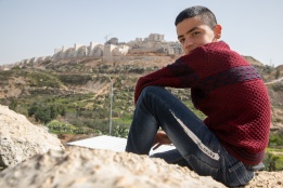 a boy in Wadi Foukin, Bitar Illit settlement in the background. Photo: Bassam Almohor 